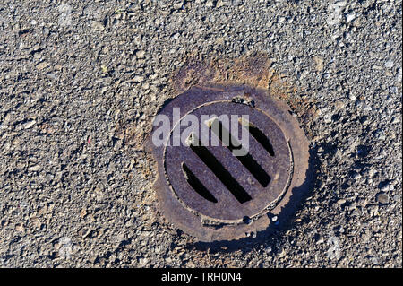 A drain is covered by a round, rusty grate Stock Photo