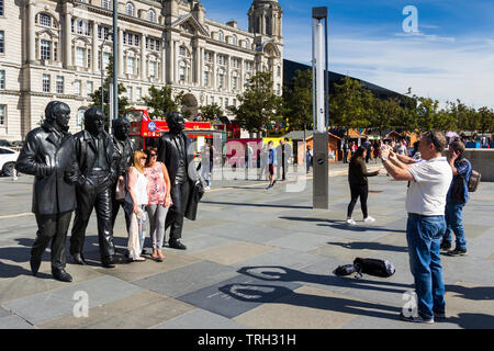 Two women posing for a photograph in front of the  Beatles statue on Liverpool's Pier Head. The statue was unveiled in December 2015. Stock Photo