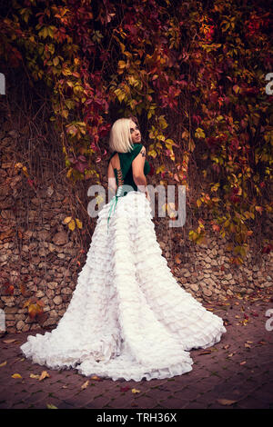 A woman like a princess in an vintage dress in fairy park. Mysterious woman dressed in scenic fashion clothes. Green labyrinth. instagram toned. Model Stock Photo