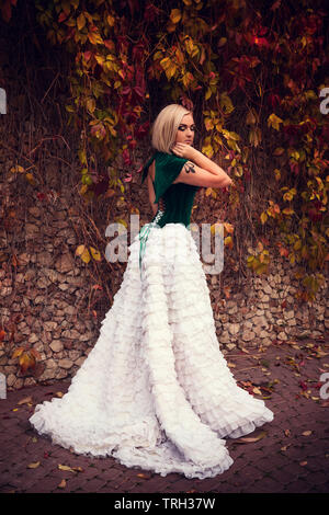 A woman like a princess in an vintage dress in fairy park. Mysterious woman dressed in scenic fashion clothes. Green labyrinth. instagram toned. Model Stock Photo