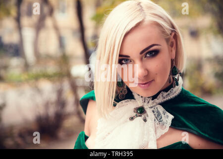 A woman like a princess in an vintage dress in fairy park. Mysterious woman dressed in scenic fashion clothes. Green labyrinth. instagram toned. Model Stock Photo