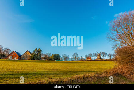 Village Vlotho on a bright sunny winter morning where the windmill and red roof cottages beautify the nature. Stock Photo