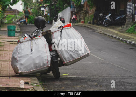 Motorcycle parking on a road near the sidewalk in Ubud, Bali Stock Photo