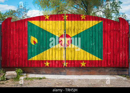 Close-up of the national flag of Grenada on a wooden gate at the entrance to the closed territory on a summer day. The concept of storage of goods, en Stock Photo