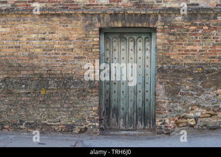 old faded turquoise weathered door in old brick wall, Newmarket, England, UK Stock Photo