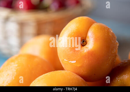 Fresh ripe armenian plums (Prunus armeniaca) on blue rustic wooden background Stock Photo