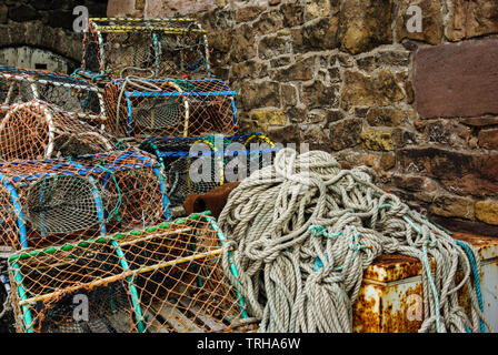 Crab and lobster pots with fishing nets on the quayside at Beadnell Harbour, Northumberland, UK Stock Photo