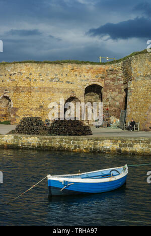 Fishing boat in Beadnell Harbour, Northumberland UK, with historic lime kilns in the background Stock Photo