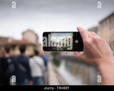 Milan, Italy - April 19, 2019: Tourist taking photo of Naviglio canal in Milan Italy with a mobile phone. Travel concept. Horizontal view Stock Photo