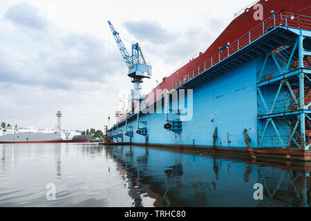 Red tanker is under repair in blue dry dock Stock Photo