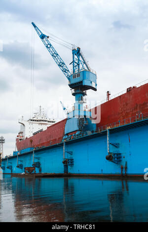 Red tanker is under repair in blue dry dock, shipyard of Varna, Bulgaria Stock Photo