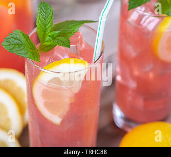 A tall glass of a refreshing raspberry cocktail, garnished with a lemon ...