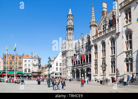 Tourists wandering around the historic market place going past the Provincial Court Provinciaal Hof in the Markt central Bruges Belgium EU Europe Stock Photo