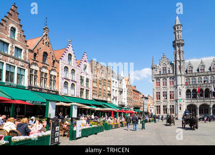Bruges Tourists in a horse drawn carriage going past the cafes near the Provincial Court Provinciaal Hof in the Markt central Bruges Belgium EU Europe Stock Photo