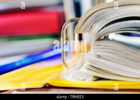 Open yellow binder close up , stack of white papers and bright metal rings , in the background colored folders Stock Photo
