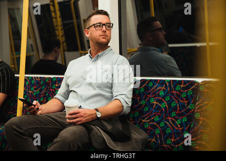 A front-view shot of a mid-adult businessman sitting on a train commuting to work in Perth, Australia. Stock Photo