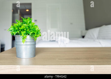 Wooden table with vintage vase plastic plant on blur bedroom Stock Photo