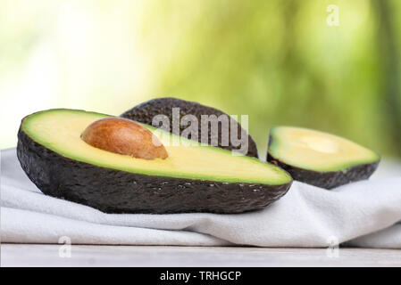 Avocados cut in half on white napkin and nature background Stock Photo