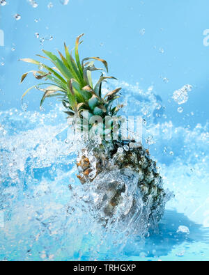 Pineapple in water splash on blue background Stock Photo