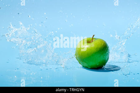 Green apple in water splash on blue background Stock Photo
