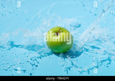 Green apple in water splash on blue background Stock Photo