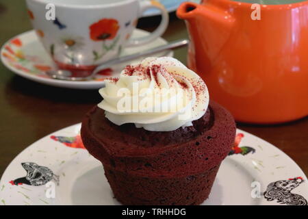 red velvet cake on a plate in a cafe setting with tea pot and a cup, ready to eat Stock Photo