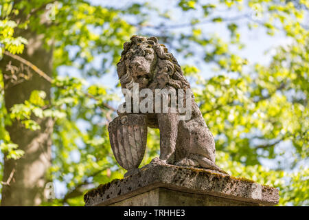 Stone statue of bavarian lion, holding a shield with the diamond pattern of the bavarian flag. The statue guards the entrance of an estate in bavaria. Stock Photo