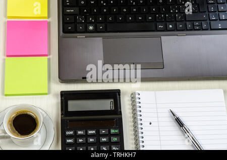tidy office table with laptop, pen, notepad,coffee cup and colorful stickers lying on the table Stock Photo