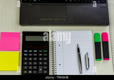 tidy office table with laptop, pen, notepad,cup of coffee and colorful stickers lying on the table Stock Photo
