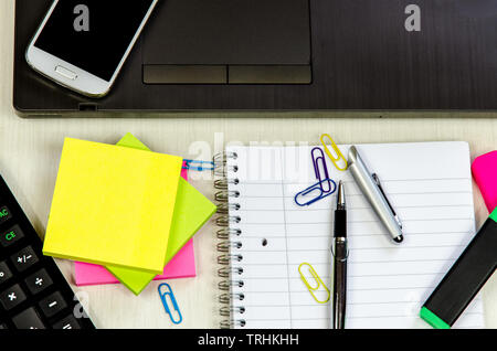 business office table with laptop, pen, notepad, smartphone and colorful stickers lying on the table Stock Photo