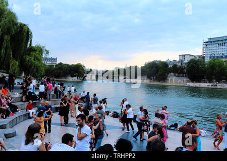 A group of people dancing and relaxing next to the Seine in Paris, France on a warm summer evening. Stock Photo