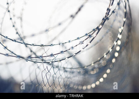 Coiled sharp barbed wire, gleaming in the light, enclosing the prison Stock Photo