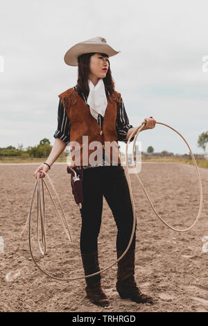 pretty Chinese cowgirl throwing the lasso in a horse paddock on a wild west farm Stock Photo