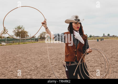 pretty Chinese cowgirl throwing the lasso in a horse paddock on a wild west  farm Stock Photo - Alamy