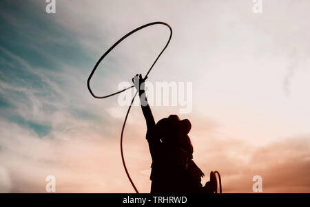 pretty Chinese cowgirl throwing the lasso in a horse paddock on a wild west farm Stock Photo