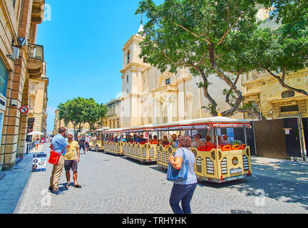 VALLETTA, MALTA - JUNE 19, 2018: The crowded St John square with Fun Train, making stop at the facade of Co-Cathedral, on June 19 in Valletta Stock Photo