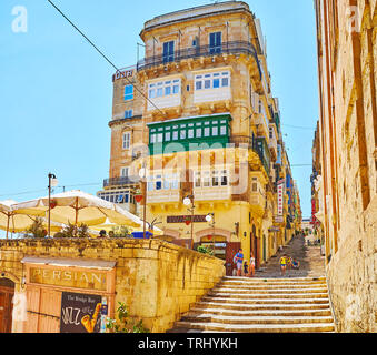 VALLETTA, MALTA - JUNE 19, 2018: The narrow hilly St Ursula street with long staircase, historic edifices, outdoor restaurants and small shops, on Jun Stock Photo