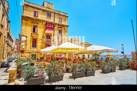 VALLETTA, MALTA - JUNE 19, 2018: The cozy outdoor terrace of the restaurant in St Ursula street of the old town, surrounded with plants in pots, on Ju Stock Photo