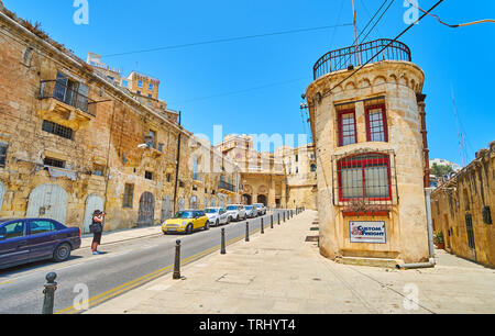 VALLETTA, MALTA - JUNE 19, 2018: Historic Liesse street is lined with old warehouses; the scenic Victoria Gate of Valletta fortifications is seen on b Stock Photo