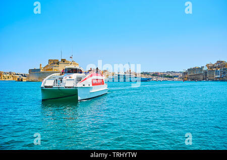 VALLETTA, MALTA - JUNE 19, 2018: The passenger ferry floats from Birgu to Valletta across the Grand Harbour with a view on Fort St Angelo on the backg Stock Photo