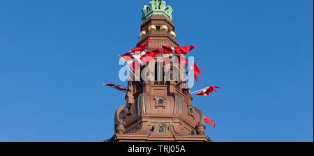 The Dannebrog, national flag of Denmark, in tower openings of Christiansborg Castle, parliament building in Copenhagen, Denmark, on special occasions Stock Photo