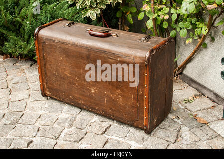 Old vintage retro grunge weathered suitcase on stone paved house backyard Stock Photo