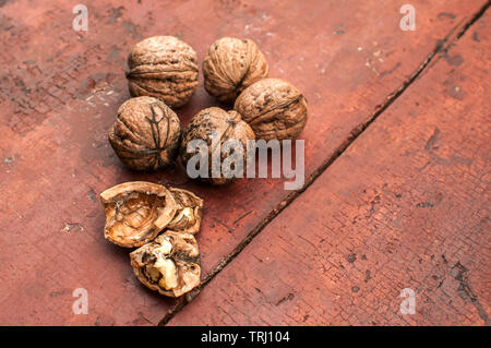 Whole and cracked walnut shells and cores closeup on old wooden boards surface as background Stock Photo