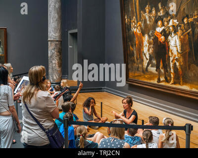 Tourist looking at The Night Watch, a painting by Rembrandt Harmenszoon van Rijn, at the Rijksmuseum in Amsterdam, The Netherlands. Rembrandt is consi Stock Photo