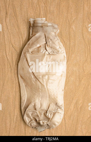 Discarded Crushed Plastic Bottle on Sand Stock Photo