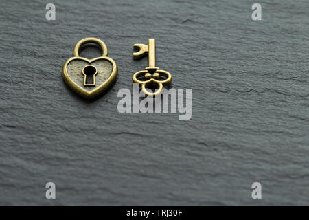 Heart-shaped padlock with key on a slate stone background . key from heart concept Stock Photo