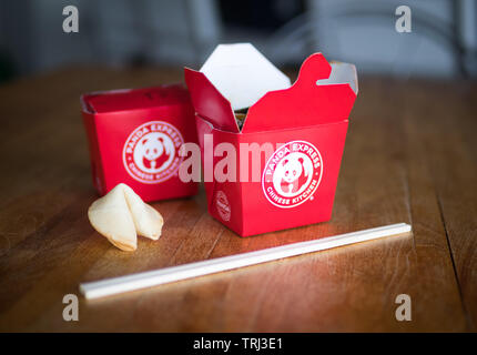 Takeout boxes of kung pao chicken from Panda Express restaurant, a fortune cookie, and chopstocks. Stock Photo