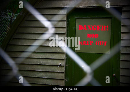 A mock up of a World War Two officer's mess showing the door with a bright red 'Danger - MOD - Keep Out' sign.. all behind a chicken wire fence. Stock Photo