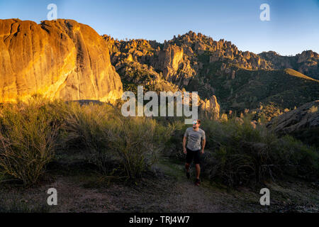 Pinnacles National Park, California - Hiker walking on trail through the hills in Pinnacles National Park during sunset. Stock Photo