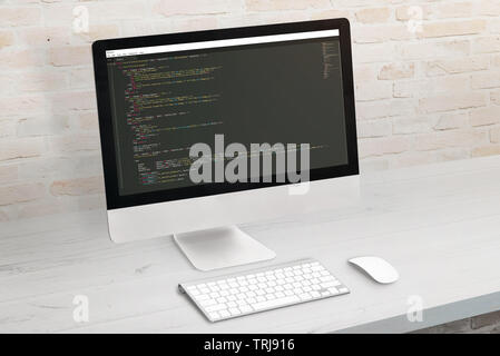 Developer computer with code on display. Clean office desk. Stock Photo